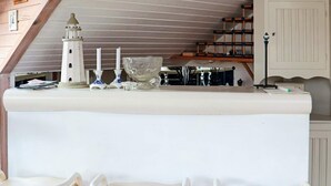 A kitchen with a white countertop, a lighthouse model, and three bar stools. - 4 Star Holiday Home in Halmstad (Halmstad)