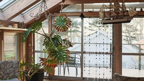 A sunroom with a large window, a potted monstera plant, and a ship model. - 4 Star Holiday Home in Halmstad (Halmstad)