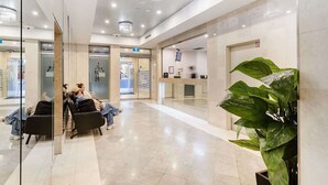 A modern lobby with a reception desk, seating area, and a large plant. - MetaWise 2Bed Next to ICC Darling Harbour 65 (Sydney)