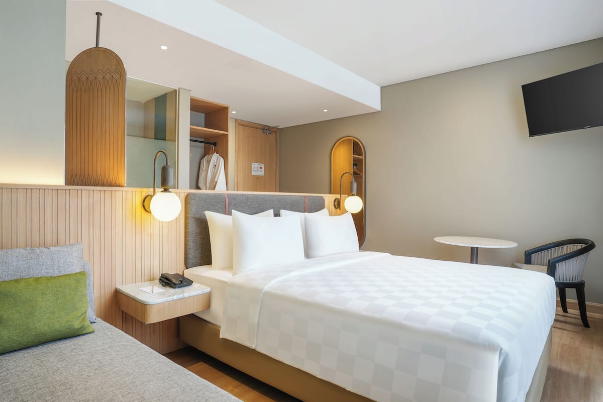 Ein Hotelzimmer mit einem Bett, einem Nachttisch, einer Lampe und einem kleinen runden Tisch mit einem Stuhl.