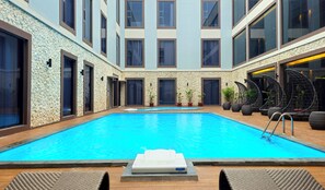 Ein moderner, überdachter Pool mit klarem, blauem Wasser, umgeben von Steinwänden und großen Fenstern.