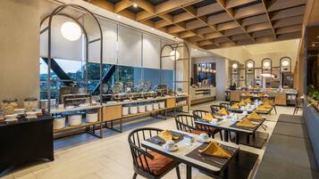 A modern restaurant with a long counter, multiple tables, and a view of the outdoors.