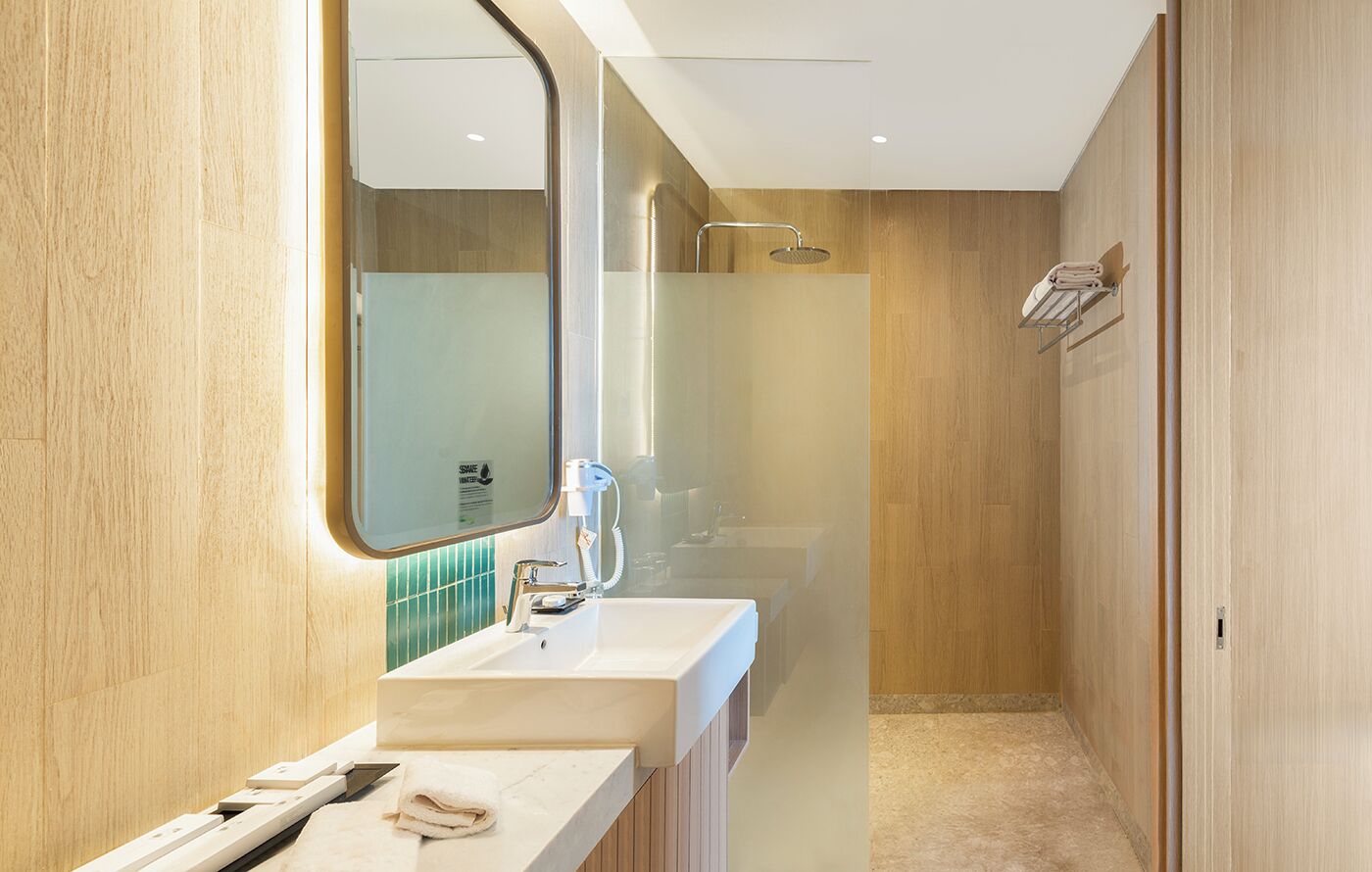 Une salle de bain moderne avec un meuble-lavabo en bois, un miroir et un espace douche.