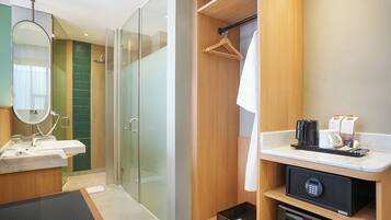 A modern bathroom with a glass shower, a sink with a mirror, and a towel hanging on a rack.