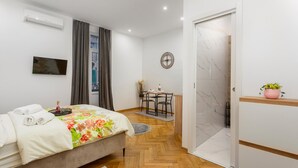 A modern bedroom with a bed, a desk, and a shower area. - Lovely apartment in Rijeka with WiFi (Rijeka)