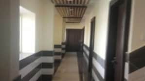 A hallway with striped walls and a tiled floor, leading to a door at the end. - HR Rama Palace (Haridwar)