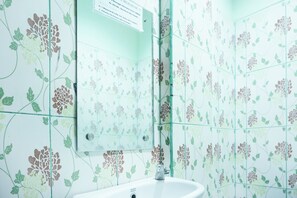A bathroom with floral patterned tiles, a white sink, and a mirror. - Hotel O Ilir Timur I Near Rsud Siti Fatimah Az-Zahra Formerly Lumendiva Suite (Palembang)