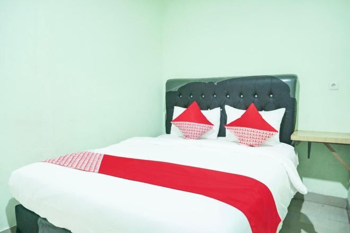A bed with a headboard, two pillows, and a blanket.