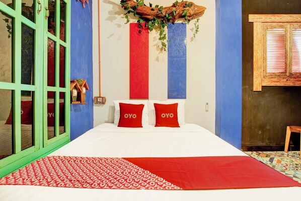 A bed with red and white bedding, two red pillows with the word "OYO" on them, and a blue and red striped wall behind the bed.