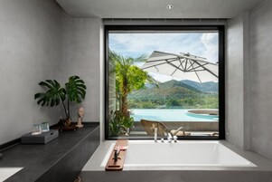 A modern bathroom with a large bathtub, a view of a mountain landscape, and a large window.
