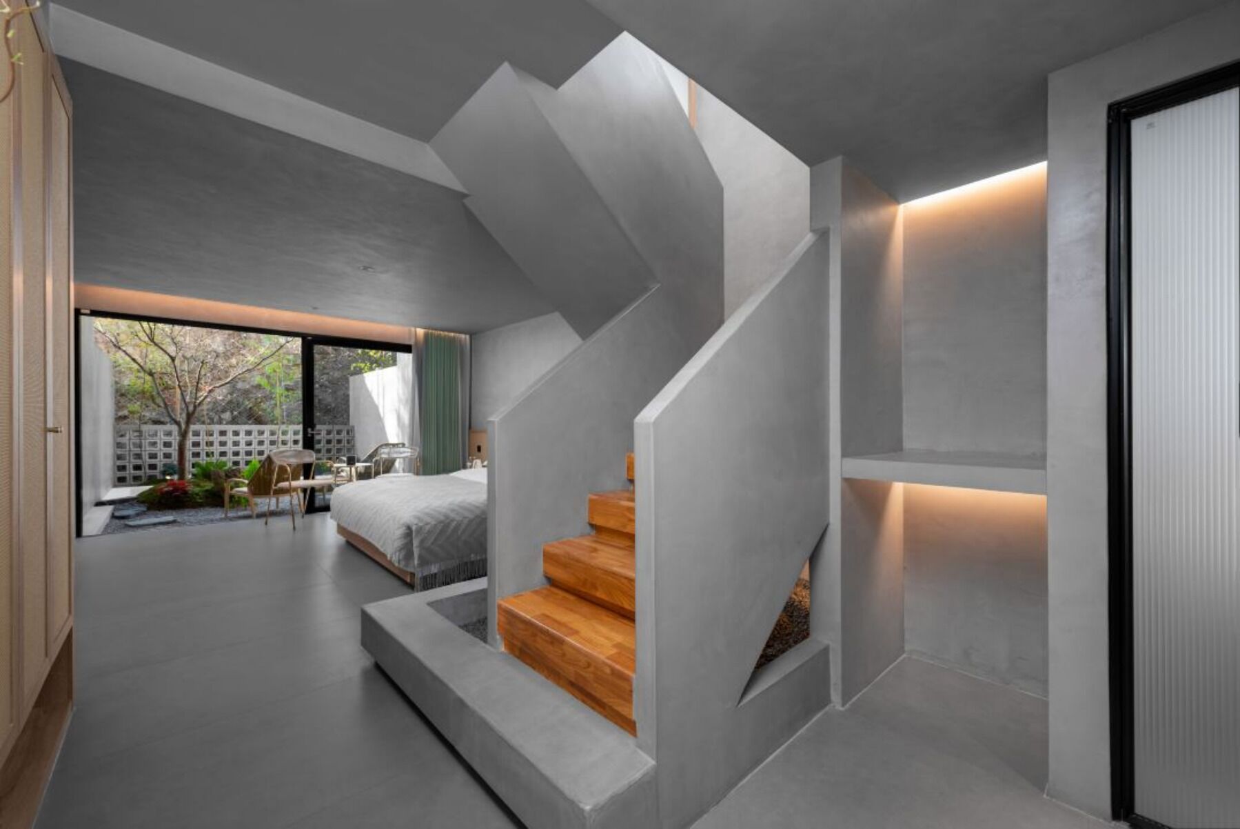Un interior moderno con una escalera que conduce a un dormitorio, un comedor con vistas amplias y un ventanal grande.