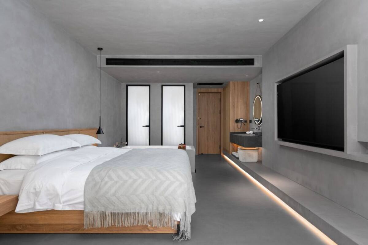 Une chambre moderne avec un grand lit, une télévision et une salle de bain avec un miroir.