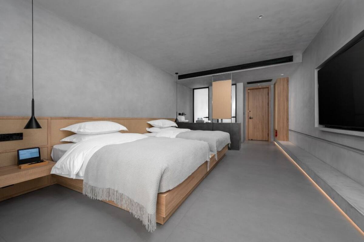 Une chambre d’hôtel moderne avec un grand lit, un bureau avec un ordinateur portable, une télévision et une grande fenêtre.