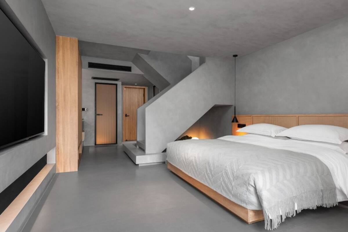 Une chambre moderne avec un grand lit, une télévision et un escalier.