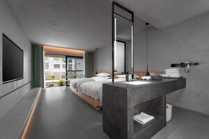 A modern hotel room with a large bed, a bathroom with a large mirror, and a view of the outdoors.