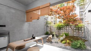 A modern interior with a concrete wall, a wooden table, and a view of an outdoor garden with trees and a fence. - HUANG GUO SHU DUO BEI YUN SHE HOTEL (Anshun)