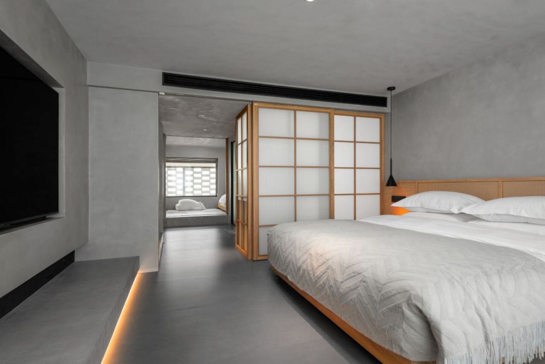 A modern bedroom with a large bed, a TV, and a sliding shoji screen door.