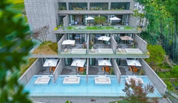 A multi-story hotel with outdoor seating areas and a swimming pool.