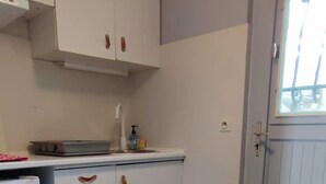Une cuisine avec des armoires blanches, un plan de travail en bois et une porte dotée d’une fenêtre.
