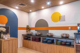 A buffet area with a variety of dishes and a decorative wall with geometric shapes.