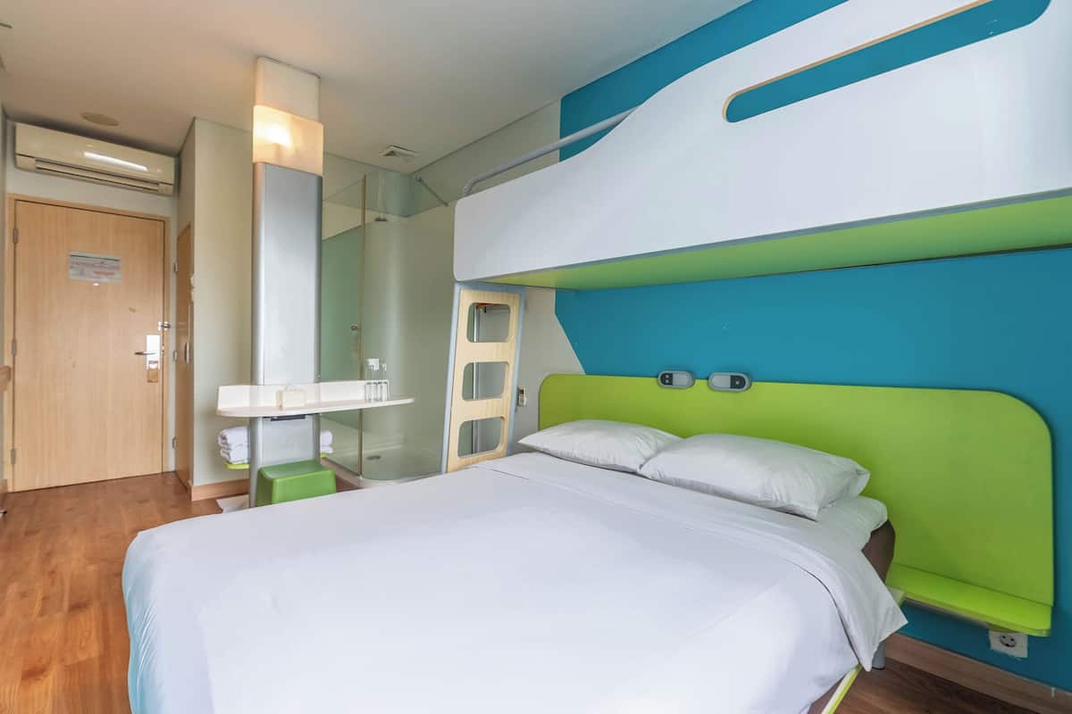 Een hotelkamer met een bed, een spiegel, een wastafel en een deur.