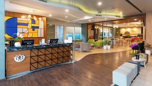 Eine moderne Hotelhalle mit Rezeption, Sitzgelegenheiten und einem Essbereich.