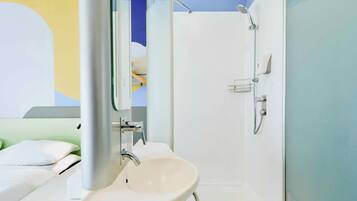 A bathroom with a white sink, a mirror, and a shower.