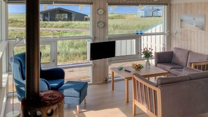 A modern living room with a large TV, comfortable seating, and a view of the outdoors. - Stunning home in Hjørring with WiFi (Hjørring)