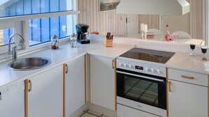 A modern kitchen with a built-in oven, a sink, and a window overlooking a blue exterior. - Stunning home in Hjørring with WiFi (Hjørring)