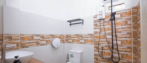 Un baño moderno con lavamanos, inodoro y ducha blancos.