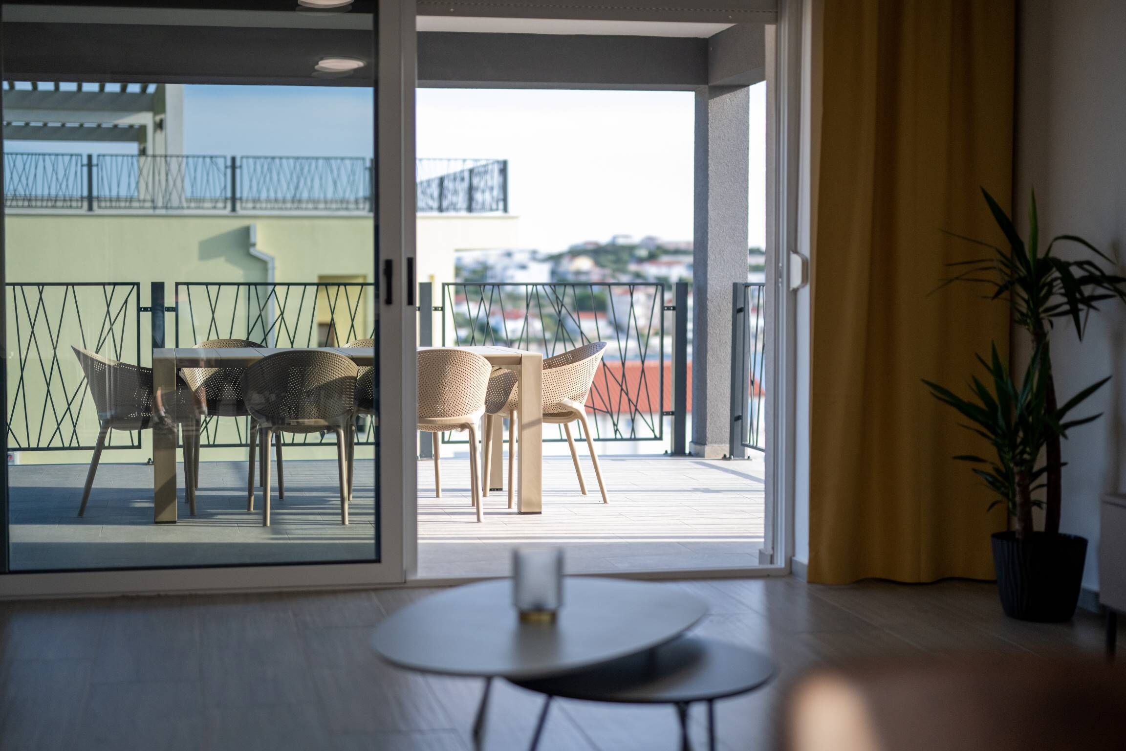 A modern room with a sliding glass door leading to an outdoor balcony with wicker furniture.