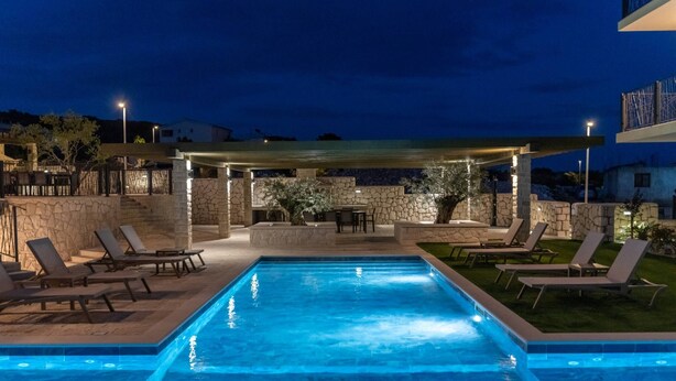 A swimming pool with lounge chairs, a covered seating area, and stone walls. - Luxury Living at Horizon Retreat (Marina)