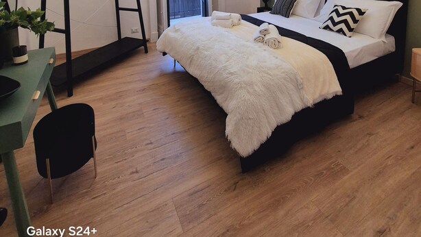 Un dormitorio con cama, escritorio, silla, lámpara colgante y equipo de aire acondicionado.