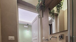 Un baño moderno con un lavabo blanco, muebles oscuros y un espejo encima.