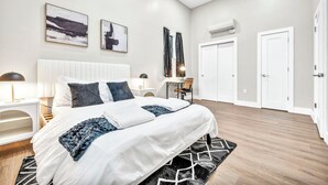 A modern bedroom with a large bed, bedside tables, a desk, and a chair. - 2Bed 1Bath 10 Min to DT Ping Pong (Cleveland)