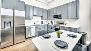 A modern kitchen with grey cabinets, stainless steel appliances, and a dining area set for four. - 2Bed 1Bath 10 Min to DT Ping Pong (Cleveland)