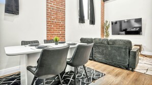 A modern living room with a white table, black chairs, a grey sofa, and a TV mounted on the wall. - 2Bed 1Bath 10 Min to DT Ping Pong (Cleveland)