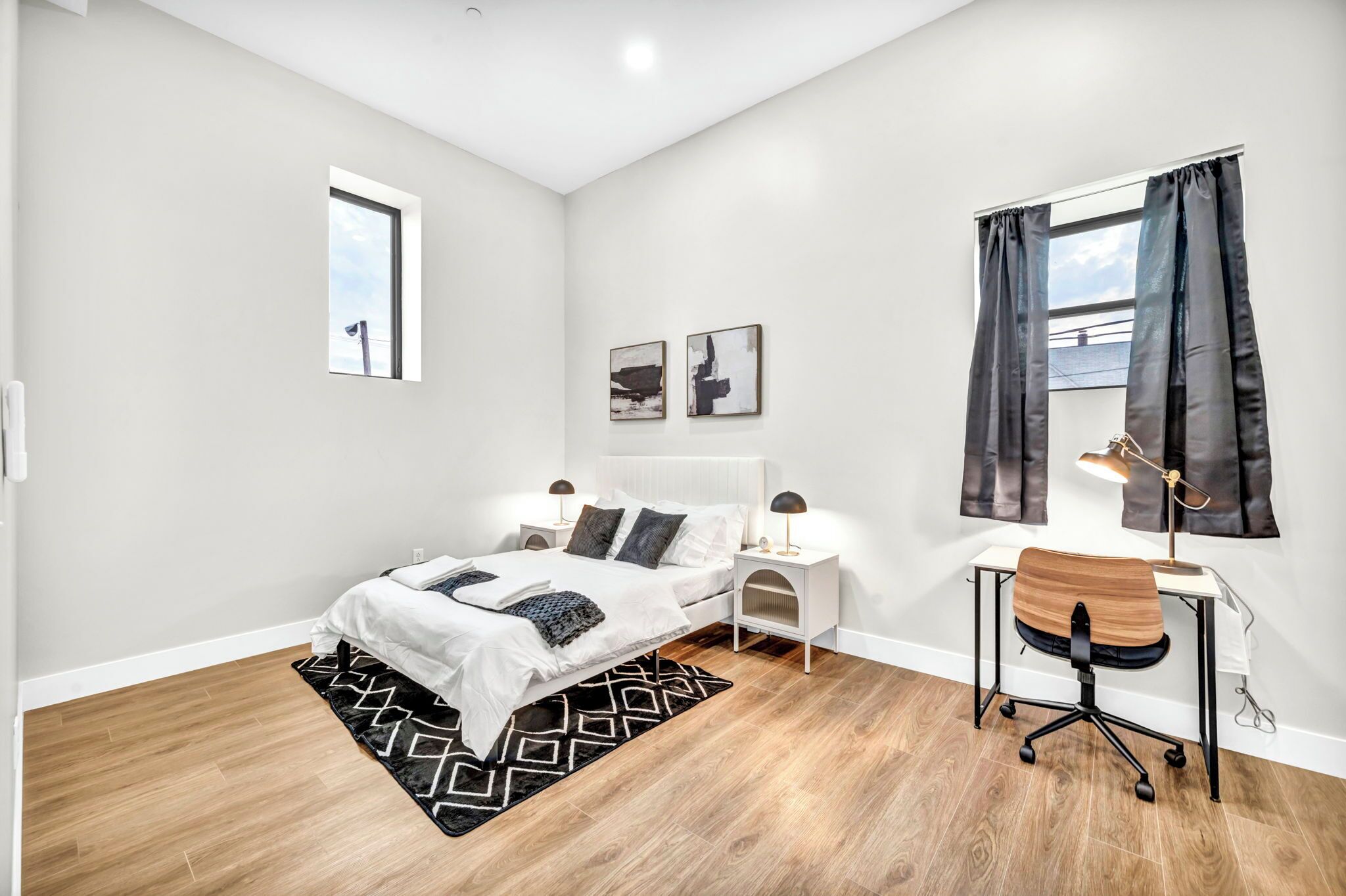 Een moderne slaapkamer met een bed, nachtkastjes, een bureau en een stoel.