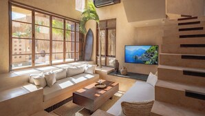 A modern room with a large window, a sofa, a TV, and a staircase. - Villa Alma at Bocoa Villas (Canggu)