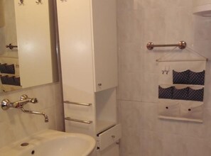 Een badkamer met een wit wastafel, een spiegel, een handdoekhouder en een zeepdispenser.