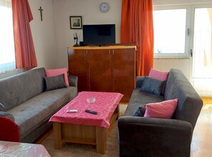 Een woonkamer met twee banken, een salontafel, een televisie en een inbouwkast.