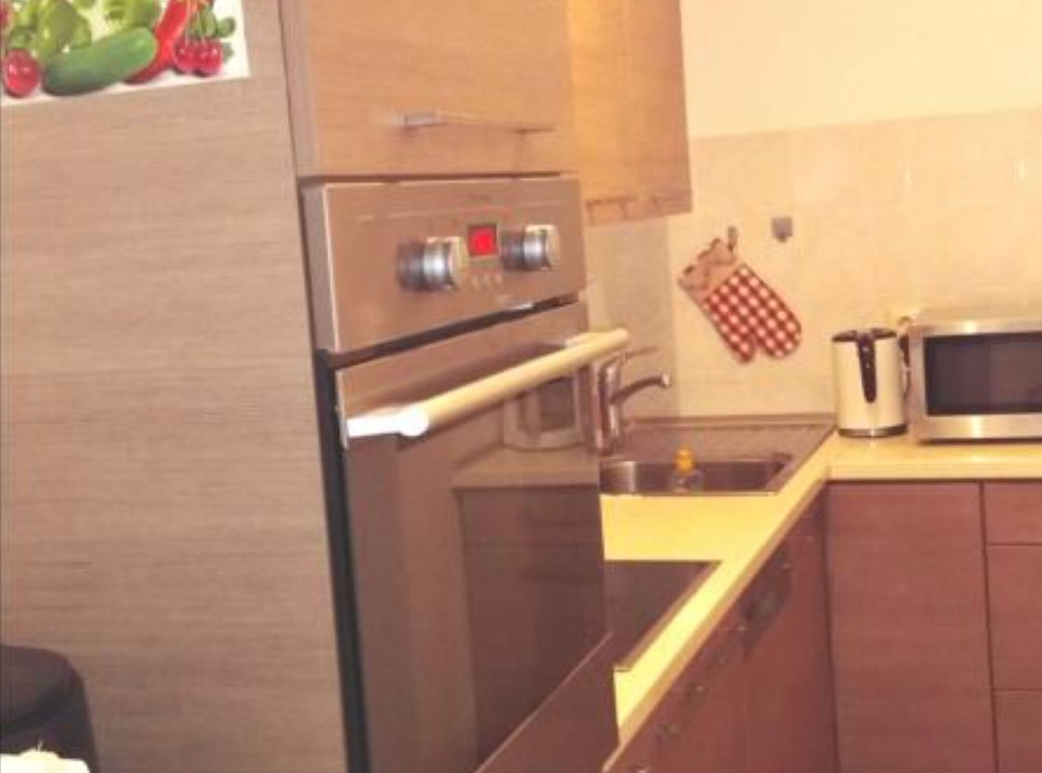 A kitchen with stainless steel appliances, a microwave, and a kettle.