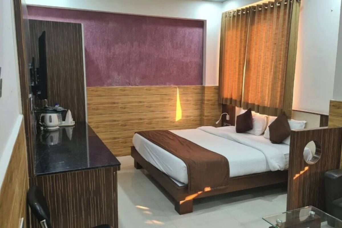 A hotel room with a bed, a desk, a chair, and a TV.