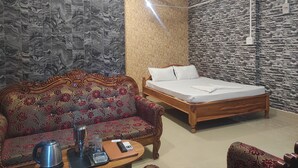 A room with a bed, a sofa, a coffee table, and a wall with a marble pattern. - Rani Guest House (Guwahati)