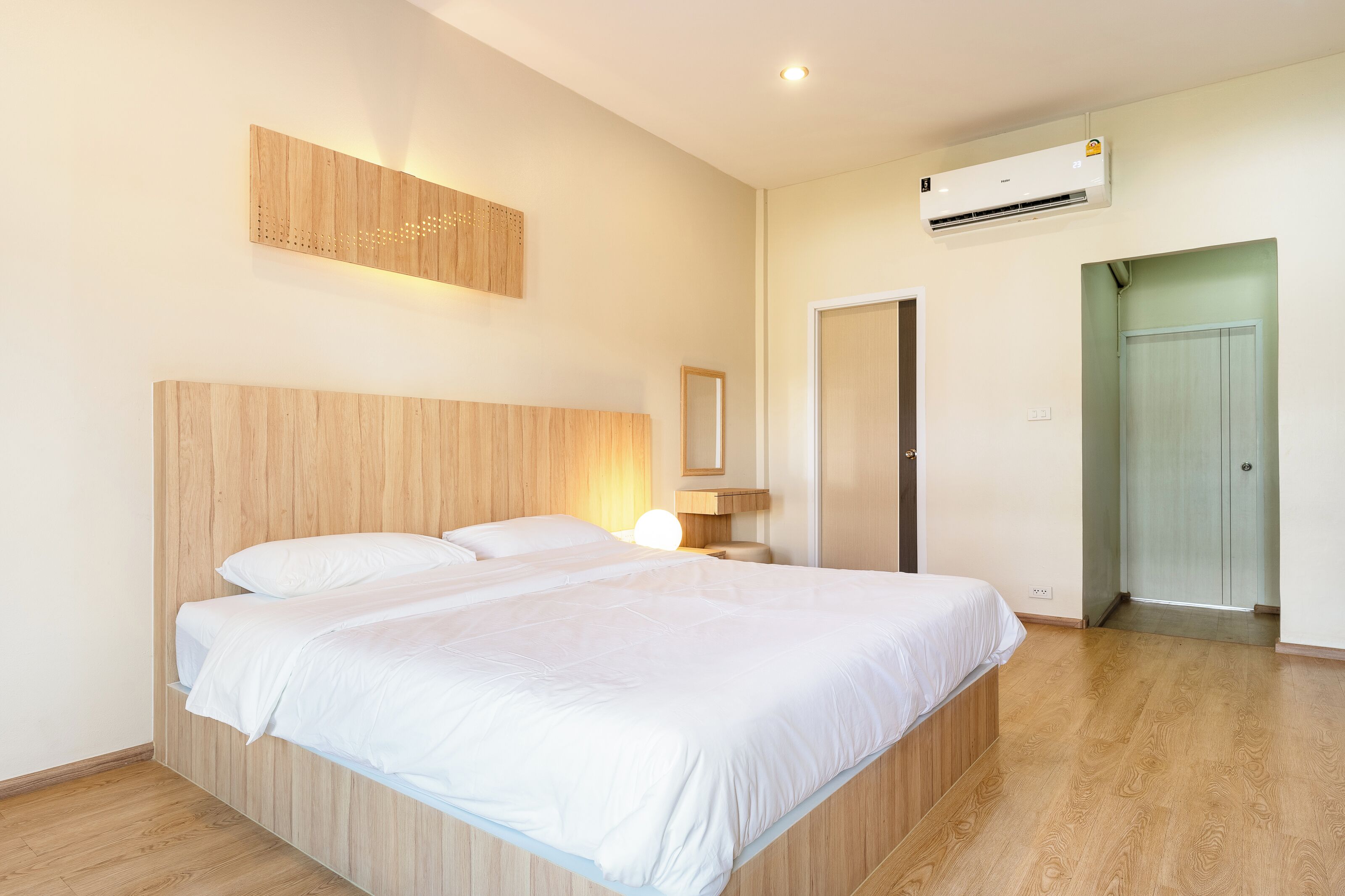 Un dormitorio moderno con una cama de madera, aire acondicionado de pared y una puerta que da a otra habitación.