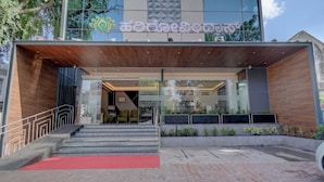 Entrada de un edificio moderno con alfombra roja, escalones y un toldo de madera.