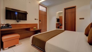 Una habitación de hotel con cama, escritorio con silla, televisor y armario.