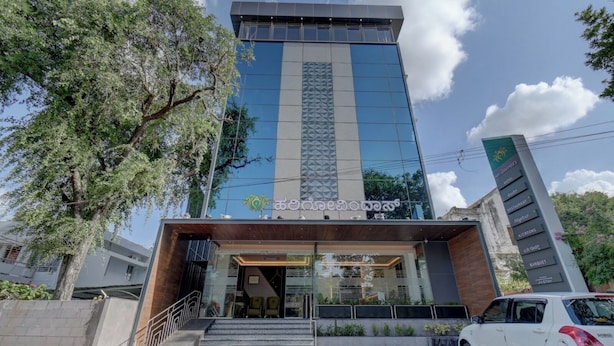 Un hotel moderno con fachada de vidrio, una escalera que lleva a la entrada y un coche estacionado al frente.