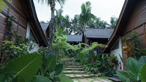 A tropical garden with stone steps leading to a wooden building. - Samujha Ubud Resort (Ubud)