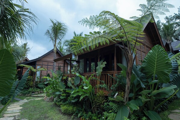 A wooden cabin surrounded by lush tropical vegetation, including large-leafed plants and ferns. - Samujha Ubud Resort (Ubud)